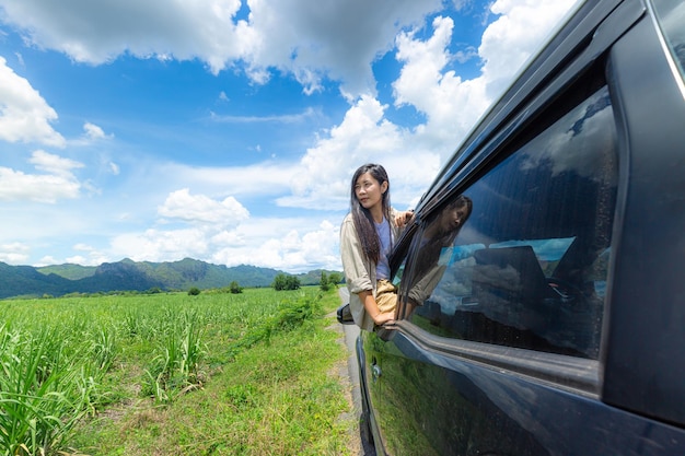 Mujer de coche en la carretera en viaje por carretera saludando feliz sonriendo por la ventana