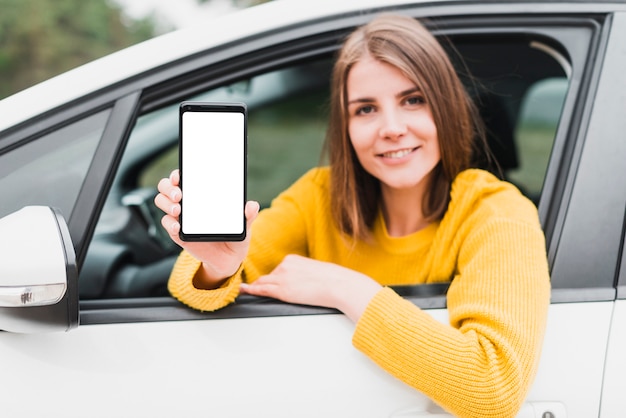 Foto mujer en el coche que muestra la pantalla del teléfono