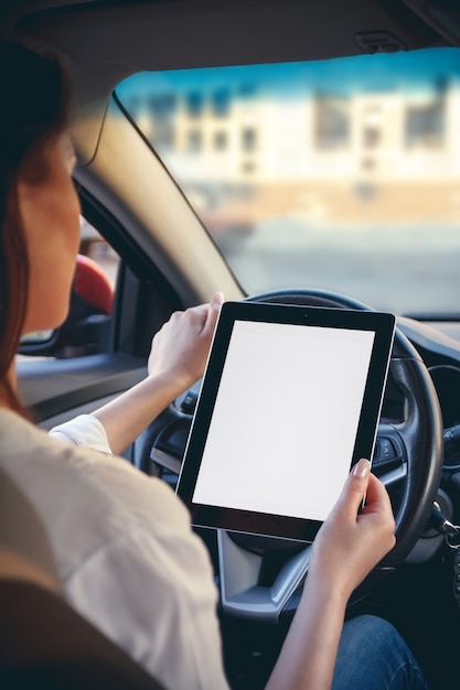 Mujer en un coche con una tableta en las manos. Concepto de conducción segura