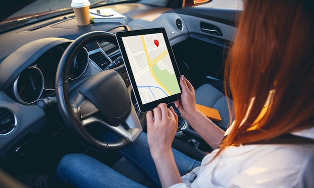 Mujer en un coche con una tableta en las manos