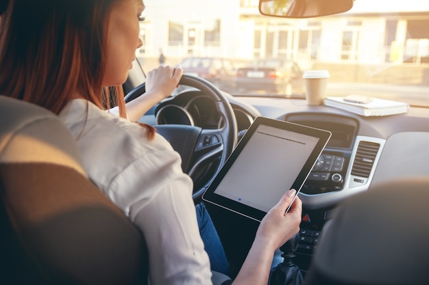 Mujer en un coche con una tableta en las manos