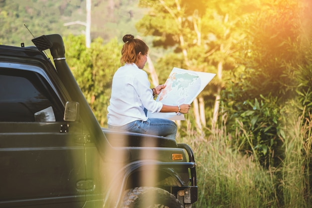 Mujer en el coche por viaje con un mapa.