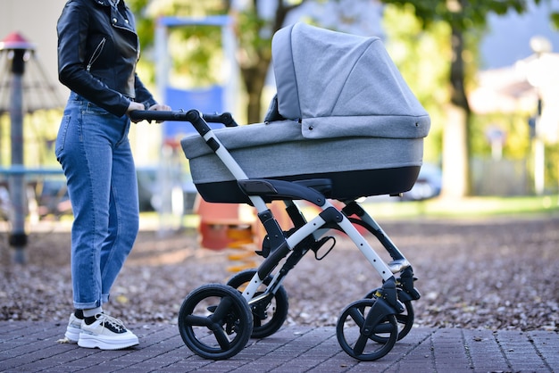 Mujer con cochecito de bebé camina en el parque al atardecer