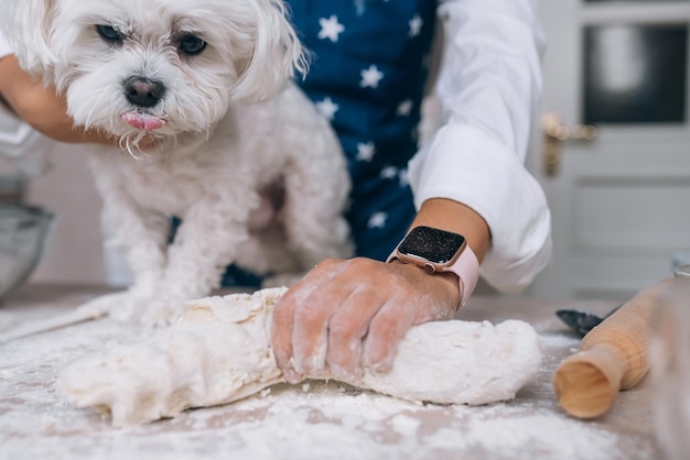 Mujer en la cocina amasa la masa con su perro