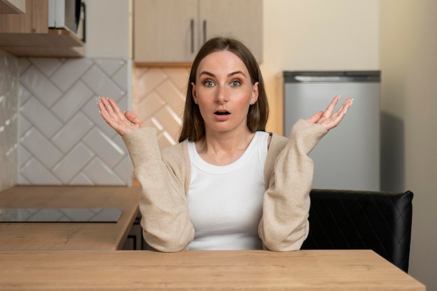 Foto la mujer en la cocina está asustada y doblada con una expresión de miedo de sorpresa y una cara emocionada