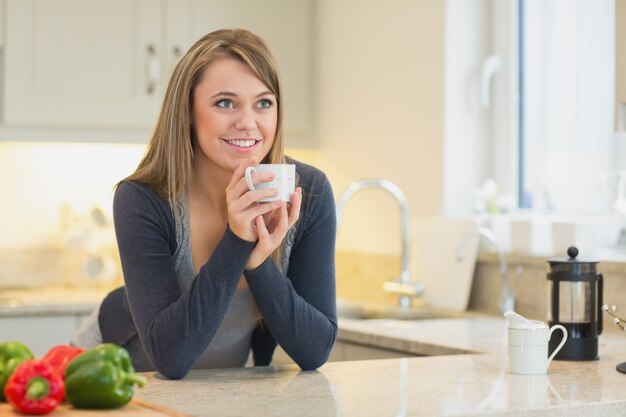 Foto mujer en la cocina bebiendo bebida caliente