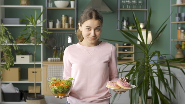 Una mujer en la cocina elige entre alimentos orgánicos saludables y donas glaseadas