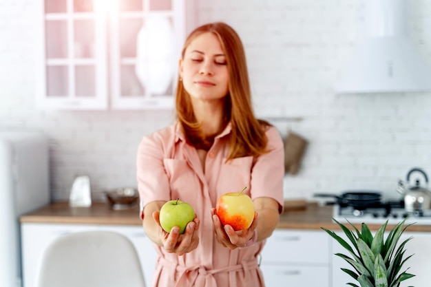 Mujer en la cocina lista para preparar comida con verduras y frutas Mujer sosteniendo manzanas Fondo de cocina Comida saludable Veganos Vegeterian Dos manzanas en las manos