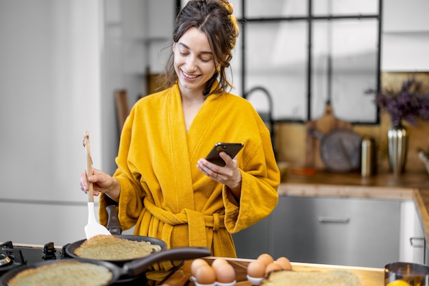 Mujer cocina panqueques para un desayuno en casa