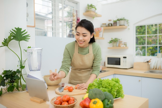 Mujer en la cocina siguiendo la receta en tableta digital