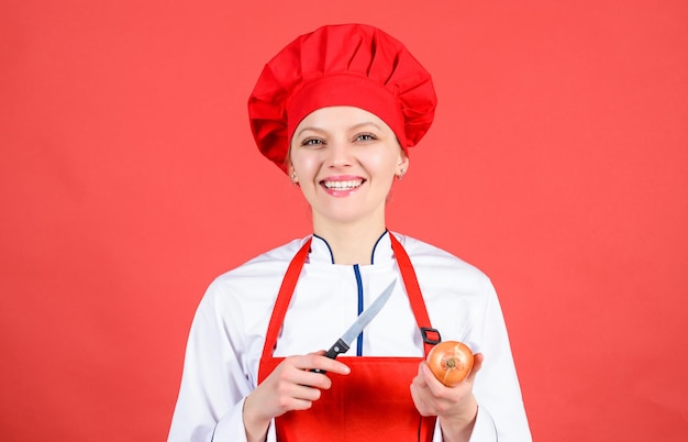 Mujer de cocina con sombrero de cocinera y delantal mujer feliz cocinando comida saludable por receta ama de casa con cuchillo de cocina y cebolla chef profesional en la cocina teniendo hambre