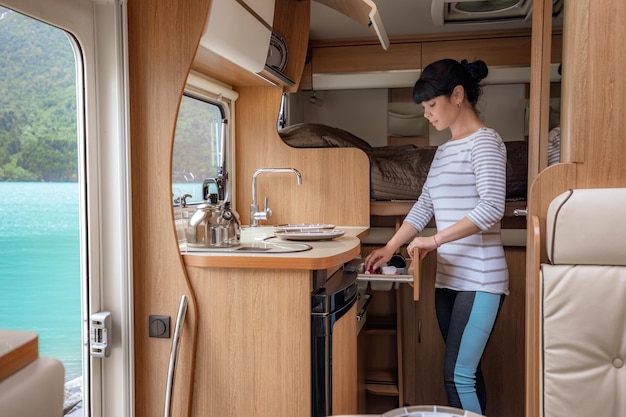 Mujer cocinando en caravana, interior de autocaravana RV. Viaje de vacaciones en familia, viaje de vacaciones en autocaravana, autocaravana de vacaciones.