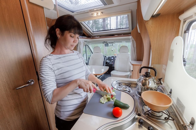 Mujer cocinando en caravana, interior de autocaravana RV. Viaje de vacaciones en familia, viaje de vacaciones en autocaravana, autocaravana de vacaciones.