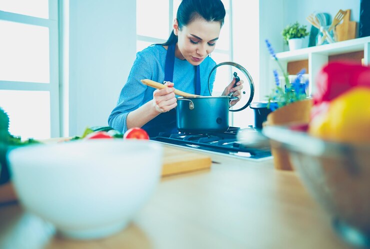 Foto mujer cocinando en la cocina con cuchara de madera