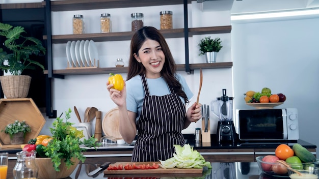 Una mujer cocinando en una cocina con pimiento amarillo.