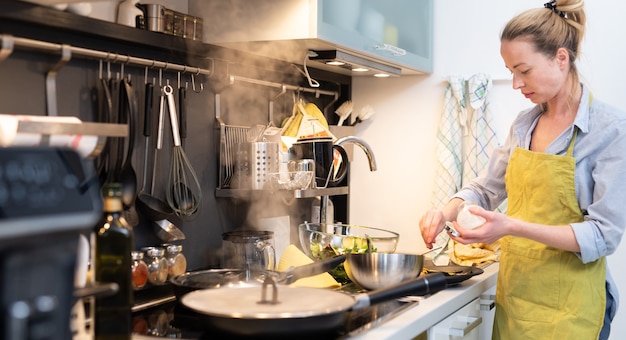 Mujer cocinando en la cocina plato de salazón en una cacerola preparando la comida para la cena familiar
