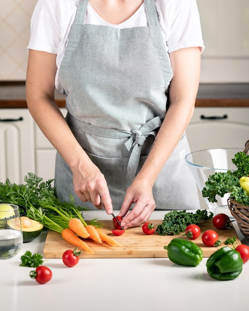 mujer cocinando en la cocina. verduras frescas y saludables en una tabla de cortar