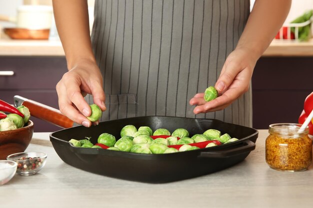 Mujer cocinando coles de bruselas en la mesa