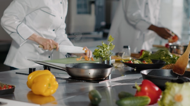 Mujer cocinando comida gourmet con rodajas de zanahorias y verduras, preparando ingredientes orgánicos para hacer un plato de restaurante profesional. auténtico chef usando recetas culinarias para cocinar. disparo de mano.