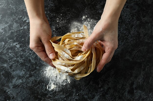 Mujer cocinando pasta sabrosa en mesa oscura