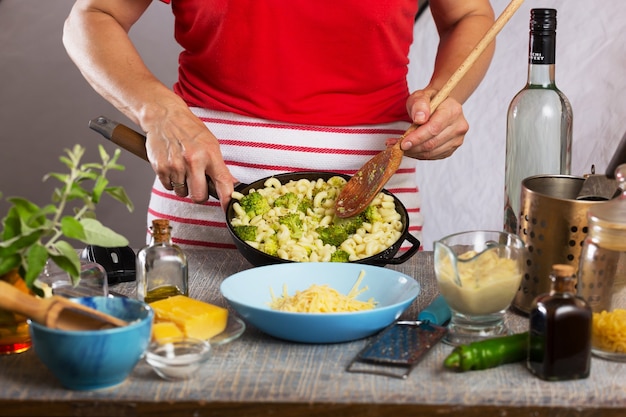 Mujer cocinando pasta con salsa de crema blanca en casa en la cocina