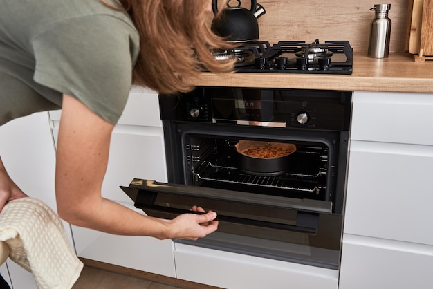 Mujer cocinando pastel en horno eléctrico