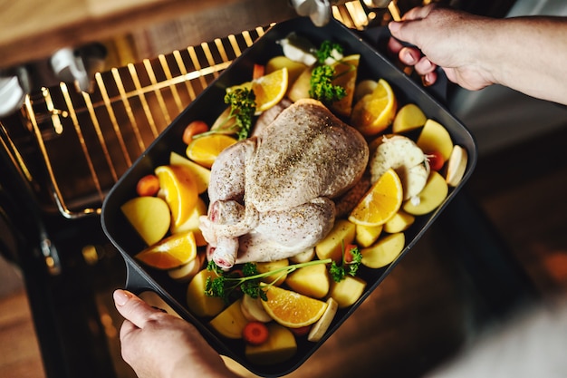 Mujer cocinando pollo crudo con verduras