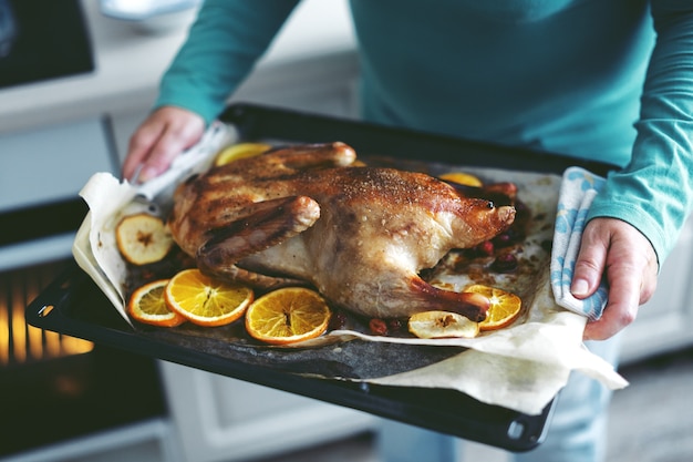 Foto mujer cocinar pato con verduras y ponerlo del horno.