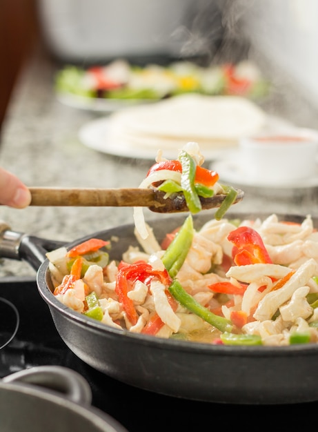 Mujer cocinar verduras y pollo en sartén