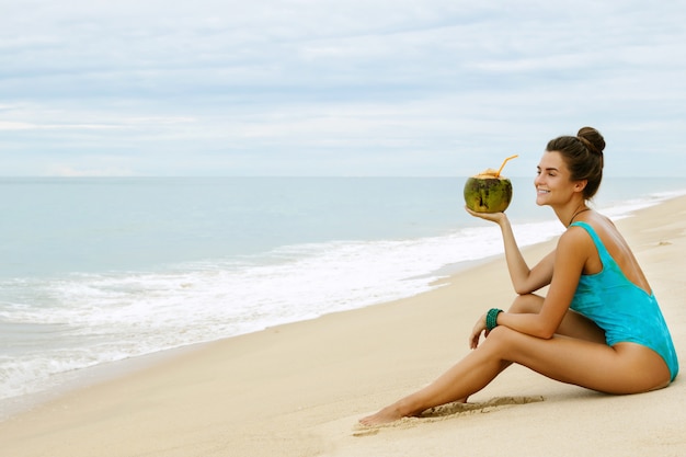 Mujer con un coco en la playa