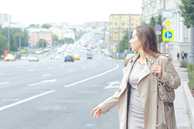 mujer coge un coche en la carretera, una joven adulta está esperando un taxi, detiene un vehículo que pasa, haciendo autostop