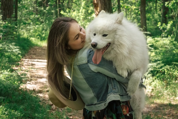 Mujer cogida de la mano y abrazando a su mullido perro samoyedo