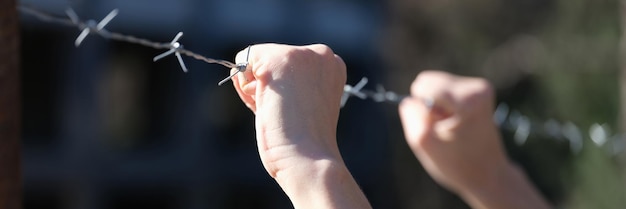 Mujer cogida de la mano en el concepto de encarcelamiento de primer plano de alambre de púas de los ciudadanos