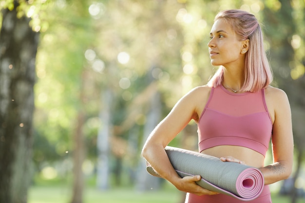 Mujer con colchoneta de ejercicios al aire libre