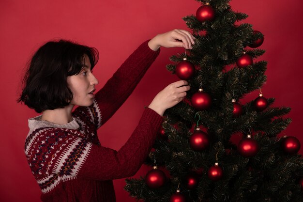 Mujer colgando bolas ornamentales en el árbol de Navidad