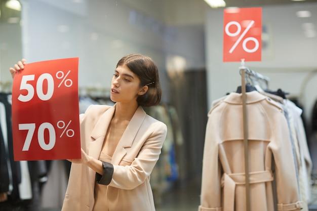 Mujer colgando carteles de venta en la tienda