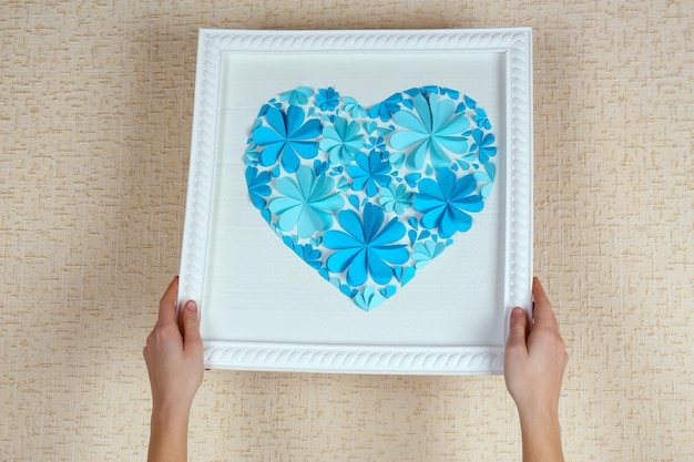 Mujer colgando un cuadro con corazón de flores de papel