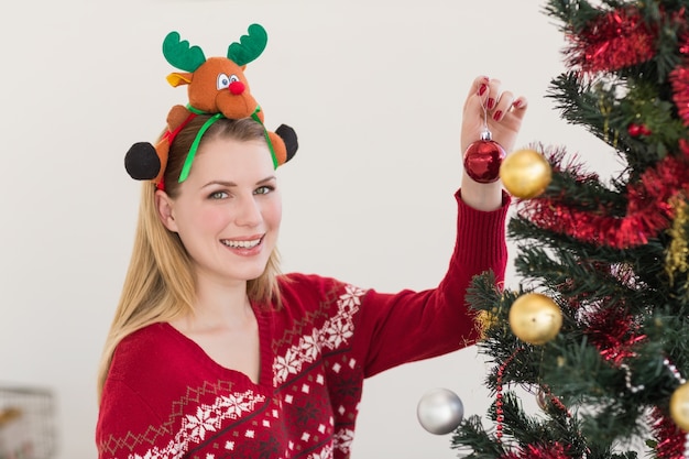 Mujer colgando decoraciones de Navidad en el árbol