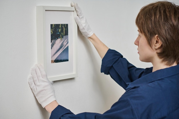 Mujer colgando foto enmarcada en la pared