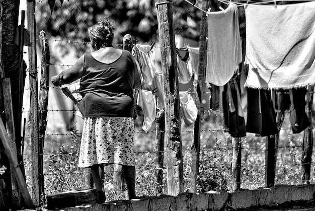 Foto mujer colgando la ropa en la valla de alambre de púas