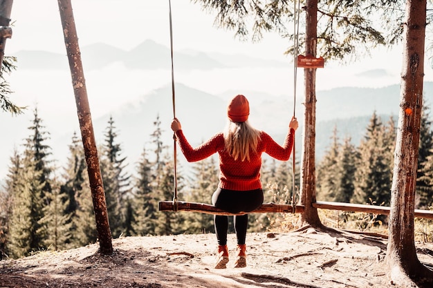 Mujer columpiándose en un columpio en un día soleado de invierno en el ferest Columpio de madera con una mujer feliz libre balanceándose al aire libre Estilo de vida saludable vacaciones Zazriva Eslovaquia