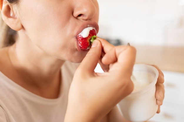 Foto mujer come bien y come fresas durante la merienda