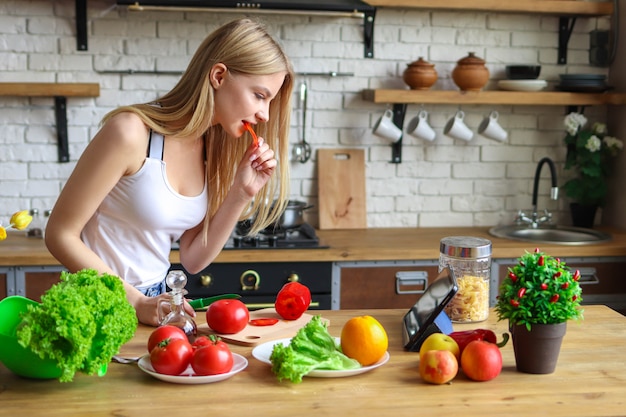 mujer come para cocinar, mujer cocina la cena en casa