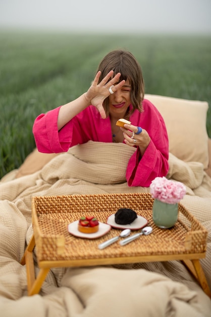 Mujer come dulces mientras se despierta en el campo al aire libre