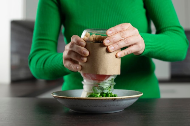 Mujer come ensalada vegana de un frasco con garbanzos Concepto de comida casera saludable