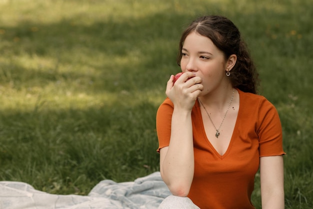 Mujer come manzana en el parque