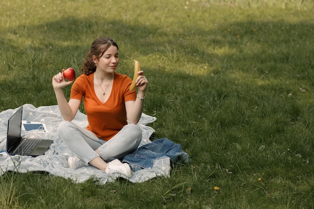 Foto la mujer come manzana y plátano en el parque