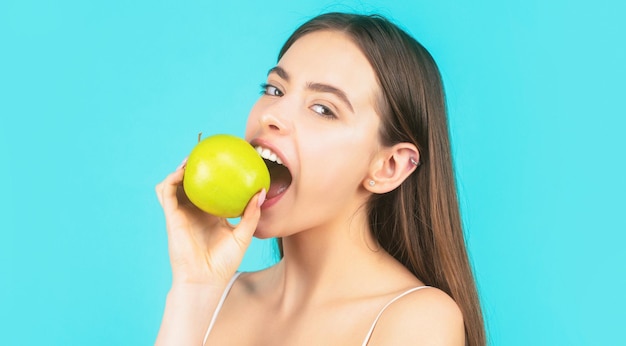 La mujer come la manzana verde. Retrato de joven hermosa mujer sonriente feliz con manzanas verdes. Alimentos de dieta saludable. Concepto de estomatología. Mujer, con, perfecto, sonrisa, tenencia, manzana, fondo azul