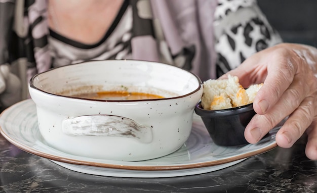 Una mujer come un plato de crema de champiñones con picatostes