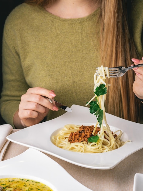 Mujer come su almuerzo en pasta de restaurante con carne